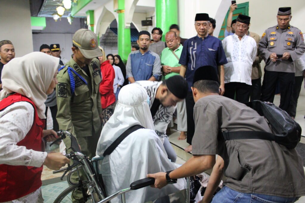 Petugas membantu jemaah haji yang menggunakan kursi roda saat tiba di halaman Masjid Raya Nur-Addin Tebing Tinggi